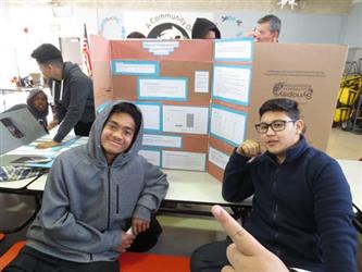 Photo of 2 students sitting in front of their science fair display board