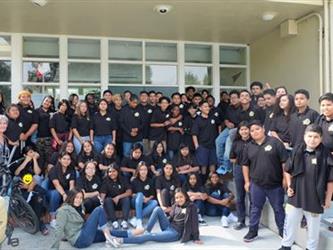 Photo of all 8th grade students wearing black Willow Oaks polo shirts standing on steps