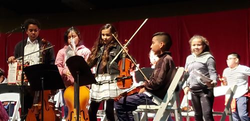 Students holding their string instruments on stage