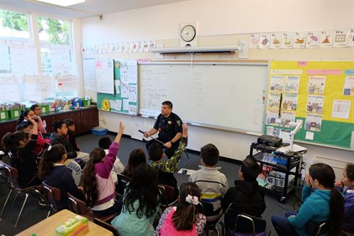 Police officer speaking to students in a classroom during mini-career day.