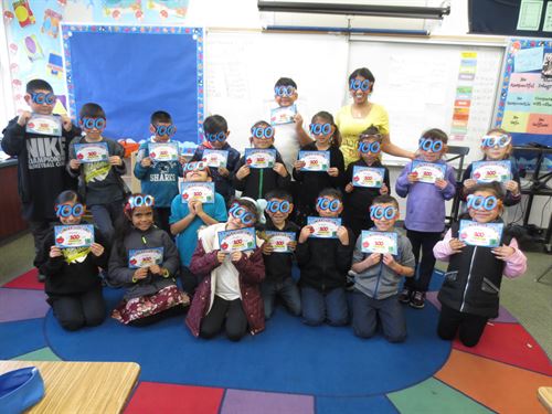 Two rows of students wearing 100 day glasses holding their 100th day of school certificate