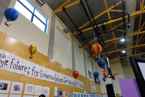 small hot air balloons in school gym with bulletin board saying "To the future